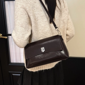 Detail of vintage dark brown leather crossbody bag with silver buckle on a model