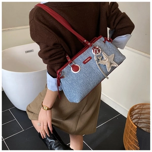 Detalle de bolso vaquero con correas de cuero rojo y colgante de estrella plateada