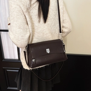 Model wearing dark coffee leather crossbody bag with silver lock and long strap
