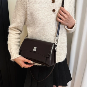 Detailed view of dark brown leather crossbody bag with silver square lock and strap detail
