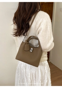 Deep brown litchi pattern leather bucket bag with silver hardware on model's shoulder