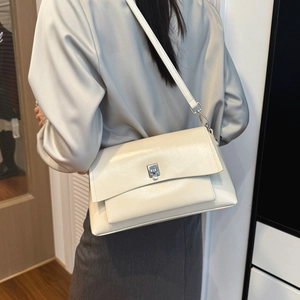 Detailed side view of a cream leather crossbody bag featuring a silver rectangular clasp
