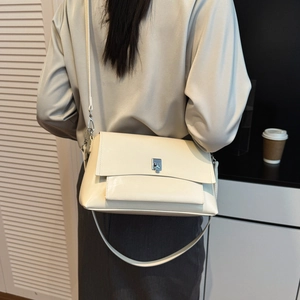 Detailed view of off-white crossbody bag with silver square twist lock and sleek leather finish