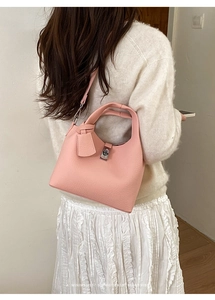 Detail showing pink lychee leather texture and metallic lock on bucket bag