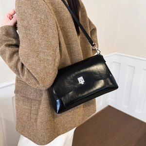 Detail of high-gloss black crossbody bag with silver clasp styled for chic office commuting