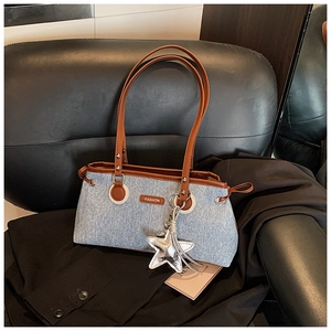 Detalle del bolso de patchwork denim y cuero marrón con colgante de estrella y tag