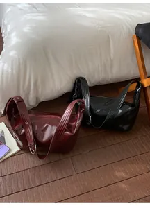 Detail of burgundy and black patent leather dumpling bags with wide eyelet straps