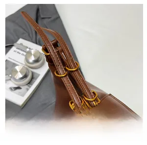 Detail of dark brown leather shoulder bag with golden rings and refined stitching