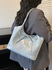 Light blue faux leather tote bag featuring a bow decoration and embossed lettering