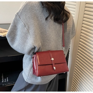 Detail view of a vintage burgundy flap shoulder bag worn with a grey knit sweater