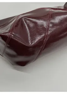 Detailed macro view of glossy burgundy oil-wax leather texture and fine red stitching