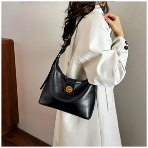 Close-up of black glossy half-moon bag with retro gold swivel lock and adjustable strap