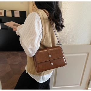 Close-up of vintage brown shoulder bag with silver buckle and decorative leather strap