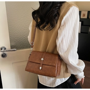 Close-up of retro brown leather rectangular crossbody bag worn over a beige outfit