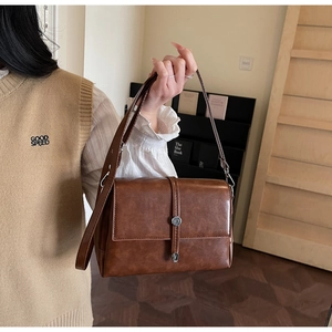 Detail view of the vintage brown leather shoulder bag with silver buckle and flap closure