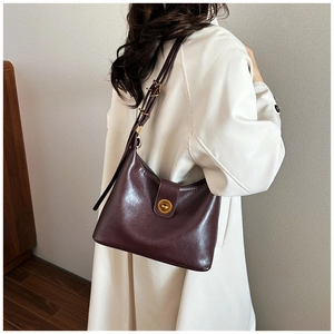 Detail of dark burgundy leather shoulder bag showing the gold metal turn-lock and texture
