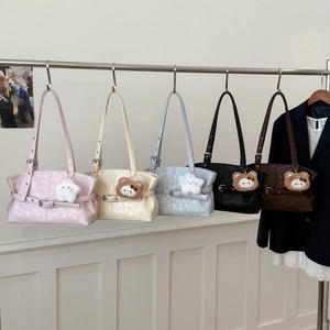 Detail view of colorful shoulder bags with decorative metal buckles and plush bear charms