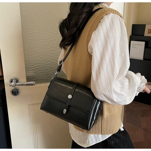 Vue détaillée d'un sac bandoulière en cuir noir avec boucle argentée sur un modèle
