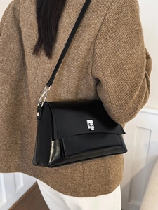 Minimalist black leather crossbody bag with silver buckle worn with a brown tweed blazer