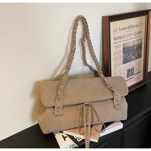 Detail of beige frosted suede shoulder bag featuring braided straps and rivet accents