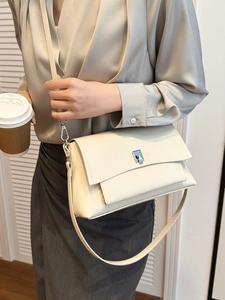 Chic cream leather crossbody flap bag with silver clasp shown in a lifestyle setting