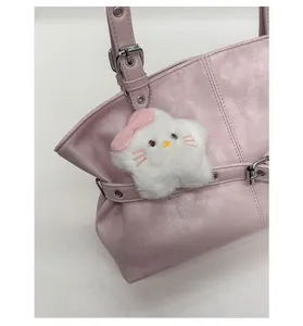Close-up of white star plush charm with pink bow on a faux leather shoulder bag strap