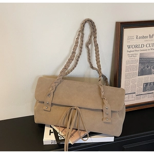 Detail of suede tote bag featuring braided shoulder straps and metal rivet accents