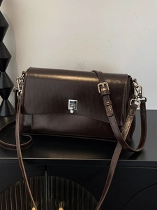 Retro chocolate brown crossbody bag with silver lock on a minimalist cabinet