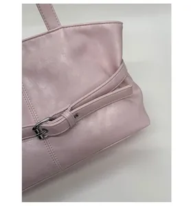 Detail of pink faux leather tote bag showing silver buckle belt and stitching