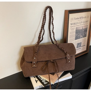 Detail of dark brown matte suede shoulder bag with woven straps and bow accent