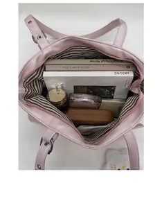 Spacious interior of pink tote bag with striped lining containing books and cosmetics