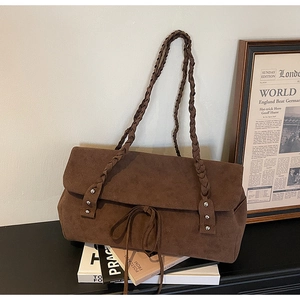 Detail of dark brown suede tote bag with woven shoulder straps and bow knot decoration