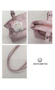 Detail of pink shoulder bag showing silver zipper, strap buckle and plush cat charm