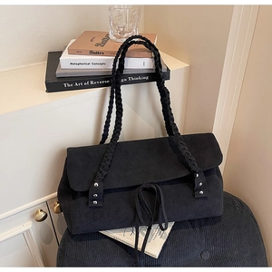 Detail of black suede shoulder bag with woven strap and silver rivets in a retro style