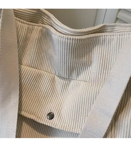 Close-up of cream corduroy tote bag showing thick ribbed texture and metal buckle detail