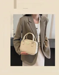 Detail view of a cream PU leather square handbag with dual handles and metal accent