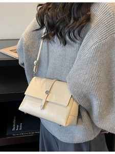 Minimalist beige leather shoulder bag with silver round buckle shown in lifestyle setting