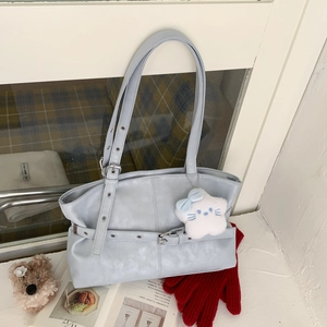 Detail of light blue faux leather shoulder bag with metal grommet straps and star pendant
