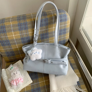 Detail of light blue faux leather shoulder bag with plush star charm on a cozy sofa