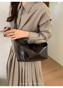 Detail of dark brown glossy leather crossbody bag featuring geometric stitching and retro style