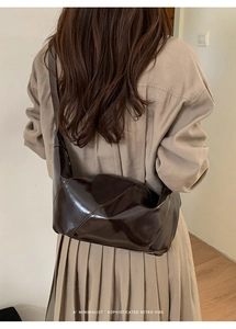Detail of dark brown glossy retro tote bag worn over the shoulder with a trench coat