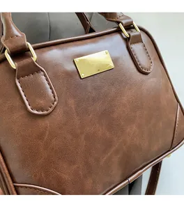 Detail of vintage brown textured leather bag with gold hardware and stitching