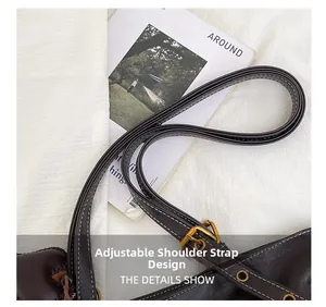 Detail view of the adjustable dark brown leather shoulder strap with golden metal buckle