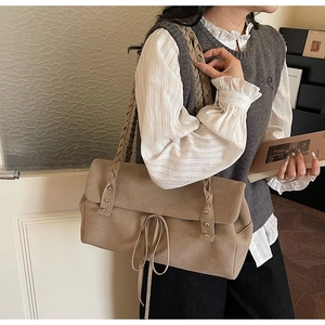 Detail view of khaki retro shoulder bag with woven straps and metal rivet accents