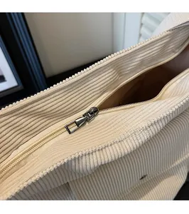 Detail view of silver metal zipper on cream corduroy tote bag with smooth texture