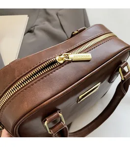 Detail of smooth gold zipper and pebble leather texture on a dark brown handbag