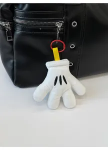 Close-up of a white plush glove pendant with black stripes on a black leather bag