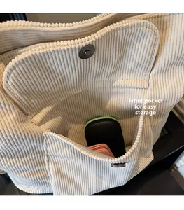 Detailed macro view of cream corduroy tote bag featuring a practical front pocket