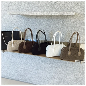 Row of plush teddy fleece handbags in various colors displayed on a wooden shelf