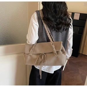 Detail of khaki frosted tote bag with woven shoulder strap and metal rivets on model